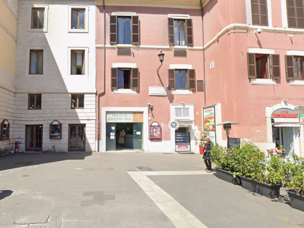 Historic building entrance with posters and plants in Italy.